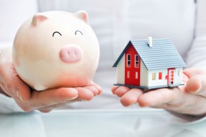 Hands holding piggy bank and  house model