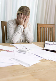 Woman working with papers with head in hands